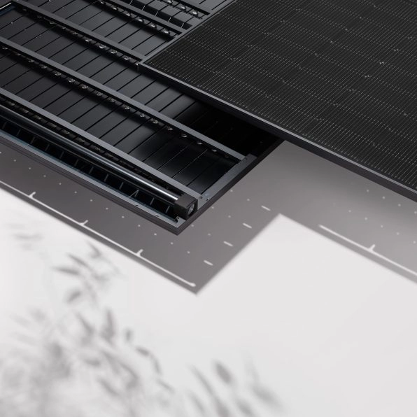 Närbild av svarta solpaneler och solhybrider installerade på ett tak med modern, minimalistisk design. Skuggor från närliggande växter syns på den ljusa ytan nedanför.